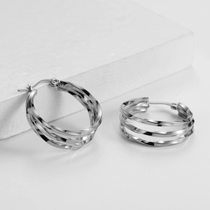 Detail of silver irregular multi-layer twisted hoop earrings on a white stone display