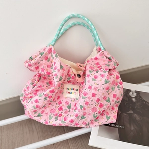 Dettaglio della borsa tote in cotone trapuntato rosa a fiori con manici verdi intrecciati