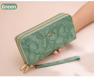 Detail of light green women's long wallet with floral embossing and gold bow charm