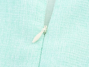 Detailed macro shot of mint green tweed fabric texture and white invisible zipper