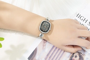 Detail of silver mesh band watch with rhinestone bezel and black oval dial