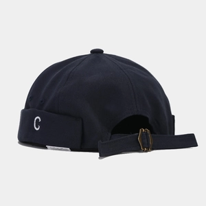 Dettaglio della fibbia in metallo e ricamo C sul cappello docker in cotone blu scuro
