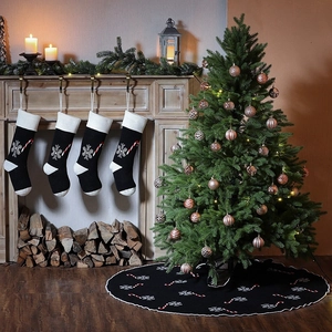 Detail of black knitted Christmas stockings and tree skirt with snowflake and candy cane patterns