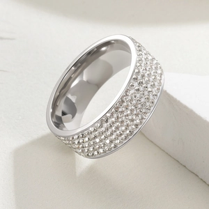 Close-up of a wide silver stainless steel ring featuring five rows of pavé set crystals