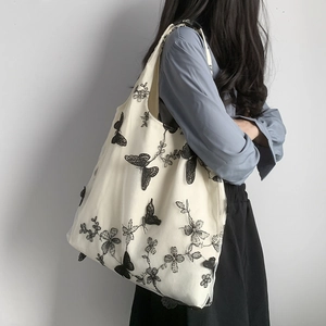 Borsa tote in tela con ricamo farfalla in rete nera indossata da una modella