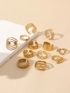 Flat lay of a 12-piece gold ring set featuring heart and eye motifs on stone props