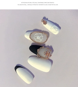 Detail of rose gold beads and white 3D flowers on black and white nail art tips