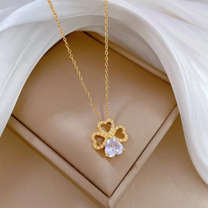 Elegant gold titanium clover heart necklace with crystals on beige jewelry box with silk