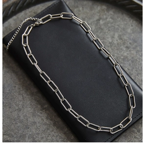 Detailed view of silver paperclip link chain with lobster clasp on black leather