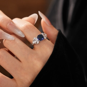 Détail d'une bague en forme de feuille avec pierre bleue carrée et zircons pavés sur argent