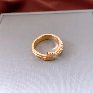 Detailed close-up of golden oval textured ring with inlaid zircons on a gray surface