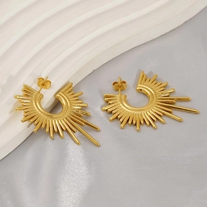 Detail shot of golden sunburst stud earrings with ray-shaped edges on satin fabric