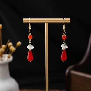 Detailed close-up of red teardrop earrings with white pearls and cloud charms