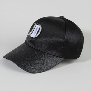 Close-up of rhinestone D logo and woven label on a black denim baseball cap
