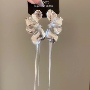 Détail des boucles d'oreilles pétales argentées avec de longues franges en métal