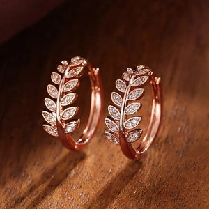 Exquisite rose gold olive leaf hoop earrings with micro-set zircons on wooden background