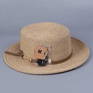 Détail du chapeau de paille avec ruban en cuir marron et boucle métallique dorée chic