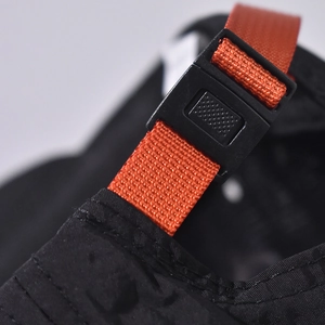 Close-up detail of adjustable orange strap and black buckle on quick-dry sun hat.