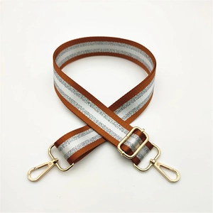 Detail of adjustable woven bag strap in brown and white with gold metal lobster clasps