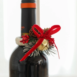 Christmas wine bottle ring with red bow, golden bell, pine cones and berries decoration