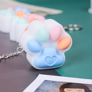 Close-up of cat paw silicone keychain with colorful macaron pads and heart engraving