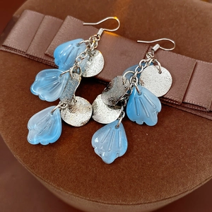 Gros plan détaillé de boucles d'oreilles à pompons en nacre avec pétales bleu clair