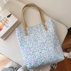 Detailed view of floral cotton tote bag featuring leather handles and metal rivets