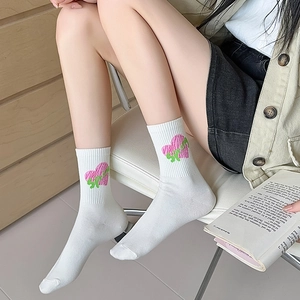 Minimalist white crew socks with pink and green heart patterns for women in a cozy setting