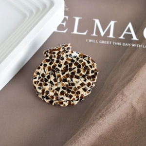 Close-up of shell-shaped acetate hair claw clip with brown tortoiseshell pattern on white tray
