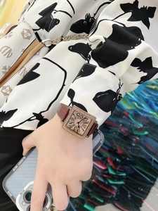 Detalle de un reloj cuadrado dorado para mujer con diamantes y correa de cuero marrón