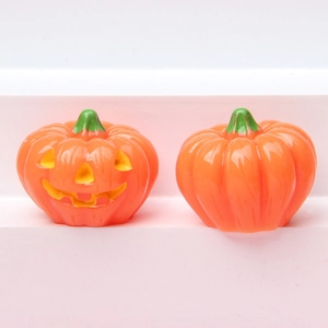 Detailed view of two orange luminous Halloween pumpkin ornaments on a pink step
