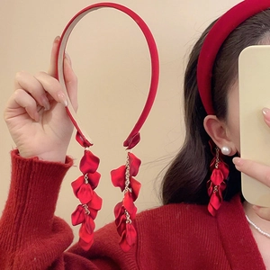 Close-up of red velvet headband with petal tassels and matching earrings on model