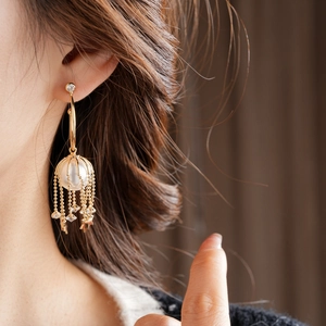 Gros plan d'une boucle d'oreille à pampilles dorées avec perle et étoiles sur mannequin