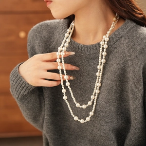 Detailed view of layered long pearl necklace on model with elegant drape and high luster
