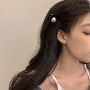 Detail view of a minimalist round pearl hair clip worn by a model on the side