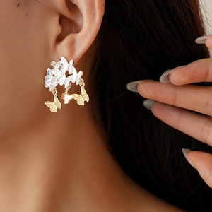 Détail de boucles d'oreilles papillon bicolores avec pampilles portées par un mannequin
