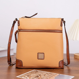 Macro view of ginger lychee textured leather crossbody bag with brown trim and metal zipper
