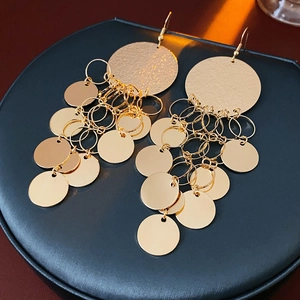 Detail of bohemian gold layered disk tassel earrings with brushed and polished textures