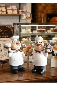 Macro shot of two chef resin figurines holding cakes in a bakery scene decoration