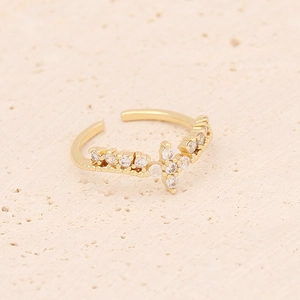 Macro detail of gold-plated cross ring with micro-pave cubic zirconia on a textured surface