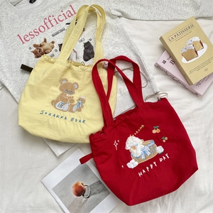Detail of yellow and red canvas tote bags featuring cute cartoon bear and dog embroidery