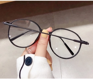 Detailaufnahme einer modischen runden schwarzen Brille handgehalten in natürlichem Licht