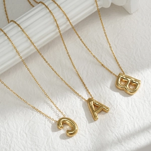 Puffy golden A B C initial necklaces with 3D balloon style pendants on white background