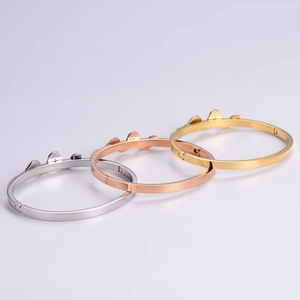 Polished 18K rose gold snake bone bangles with three diamond heart charms in three metal tones