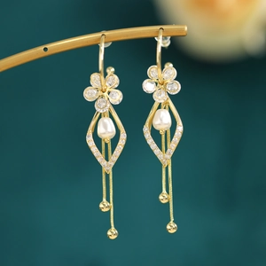 Detail of gold pearl tassel earrings with white drop pearls and floral diamond studs