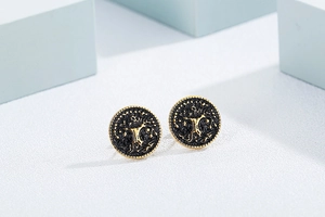 Macro detail of vintage round ear studs featuring a gold and black Tree of Life pattern