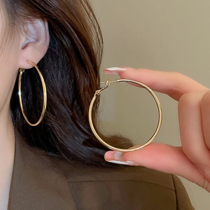 Close-up of classic large golden hoop earrings on model featuring a polished finish