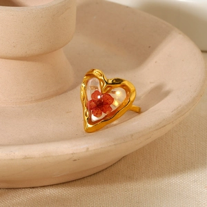 Macro detail of 18K gold ring with a real red dried flower in heart-shaped frame