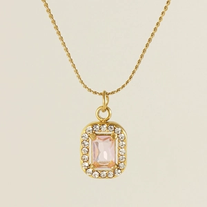 Detailed close-up of a 18K gold rectangle pendant with a pink gemstone and crystals