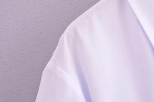 Close-up of the V-neckline and shoulder seam stitching on this white women's casual blouse